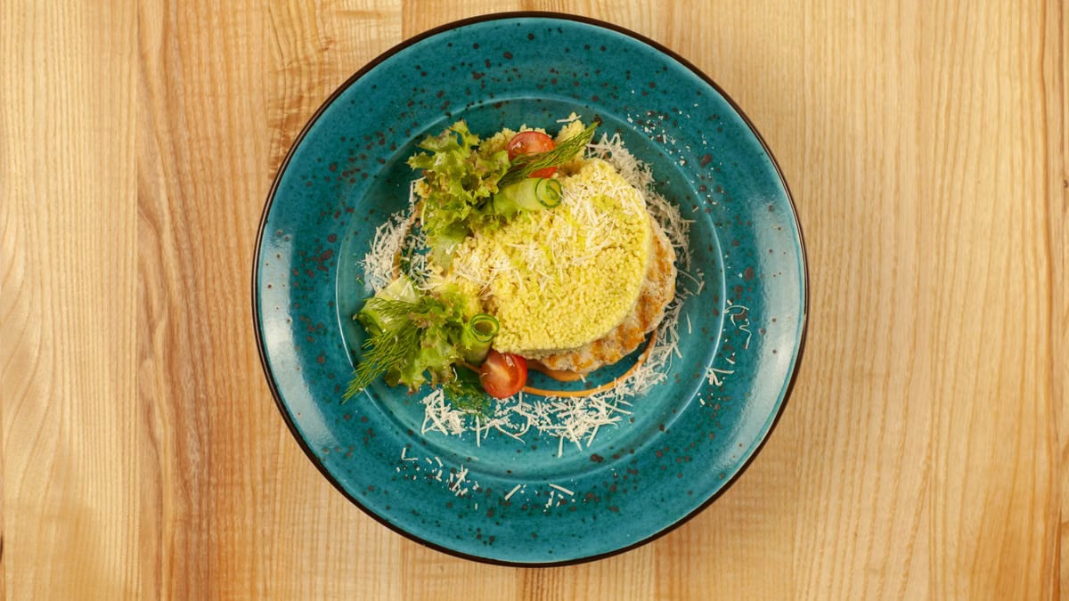 A delicious fresh salad topped with grated cheese on a blue plate.